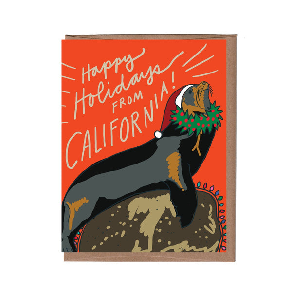 Card with a California sea lion wearing a Santa hat and wreath on an orange background with 'Happy Holidays from California!' text.